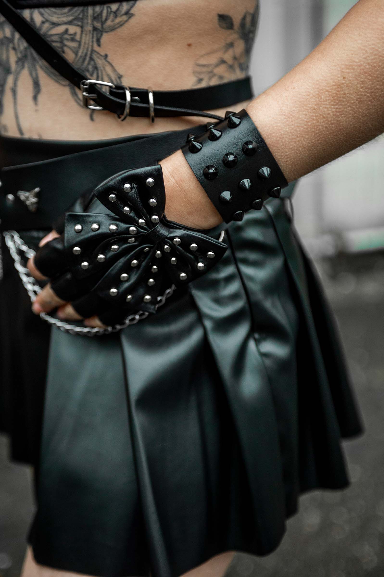 Vrouwelijk model met close up arm met bovenzijde van rave armband 'black studs'. een leren armband met zwarte studs.