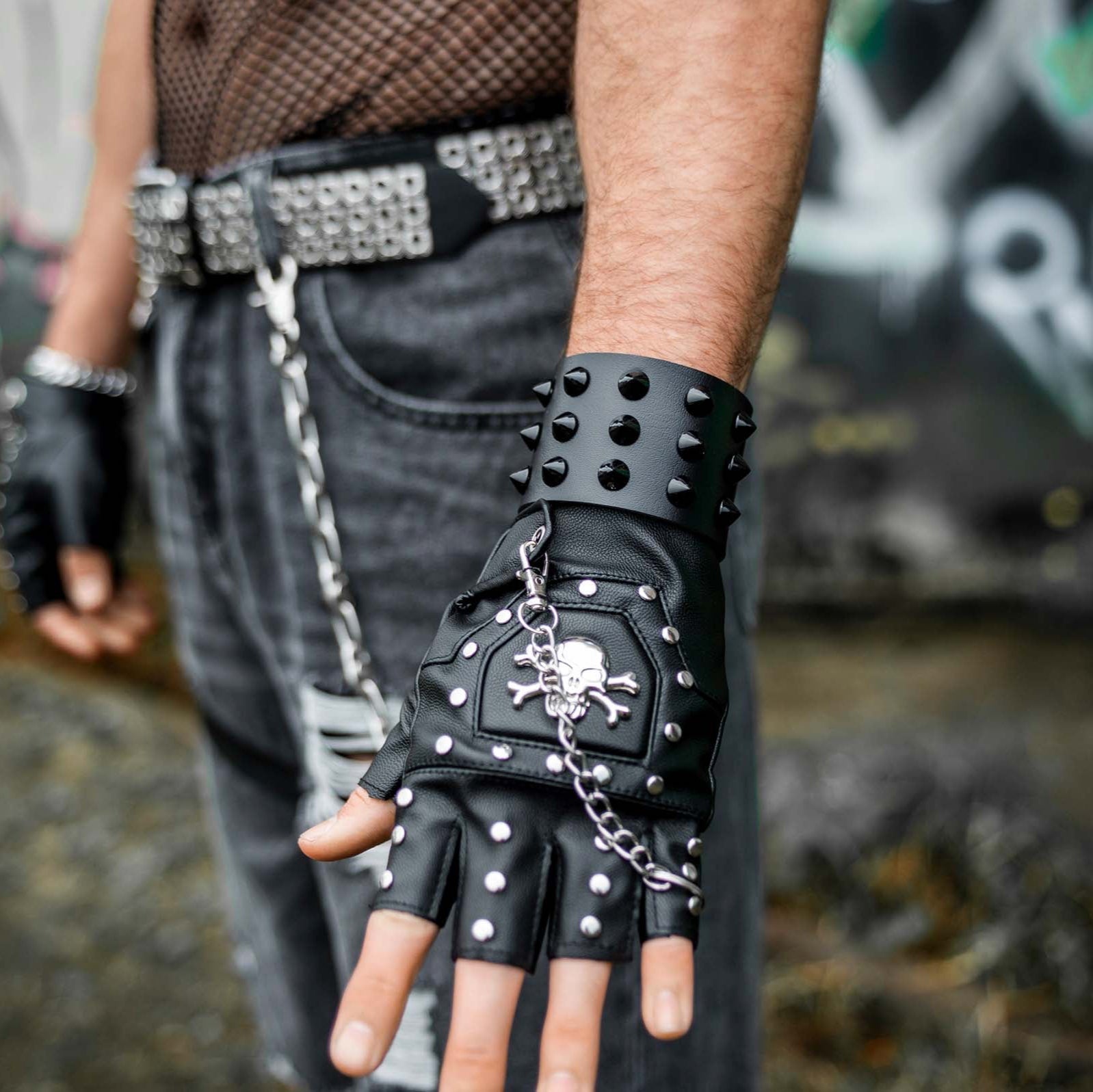 Mannelijk model met close up arm met bovenzijde van rave armband 'black studs'. een leren armband met zwarte studs.