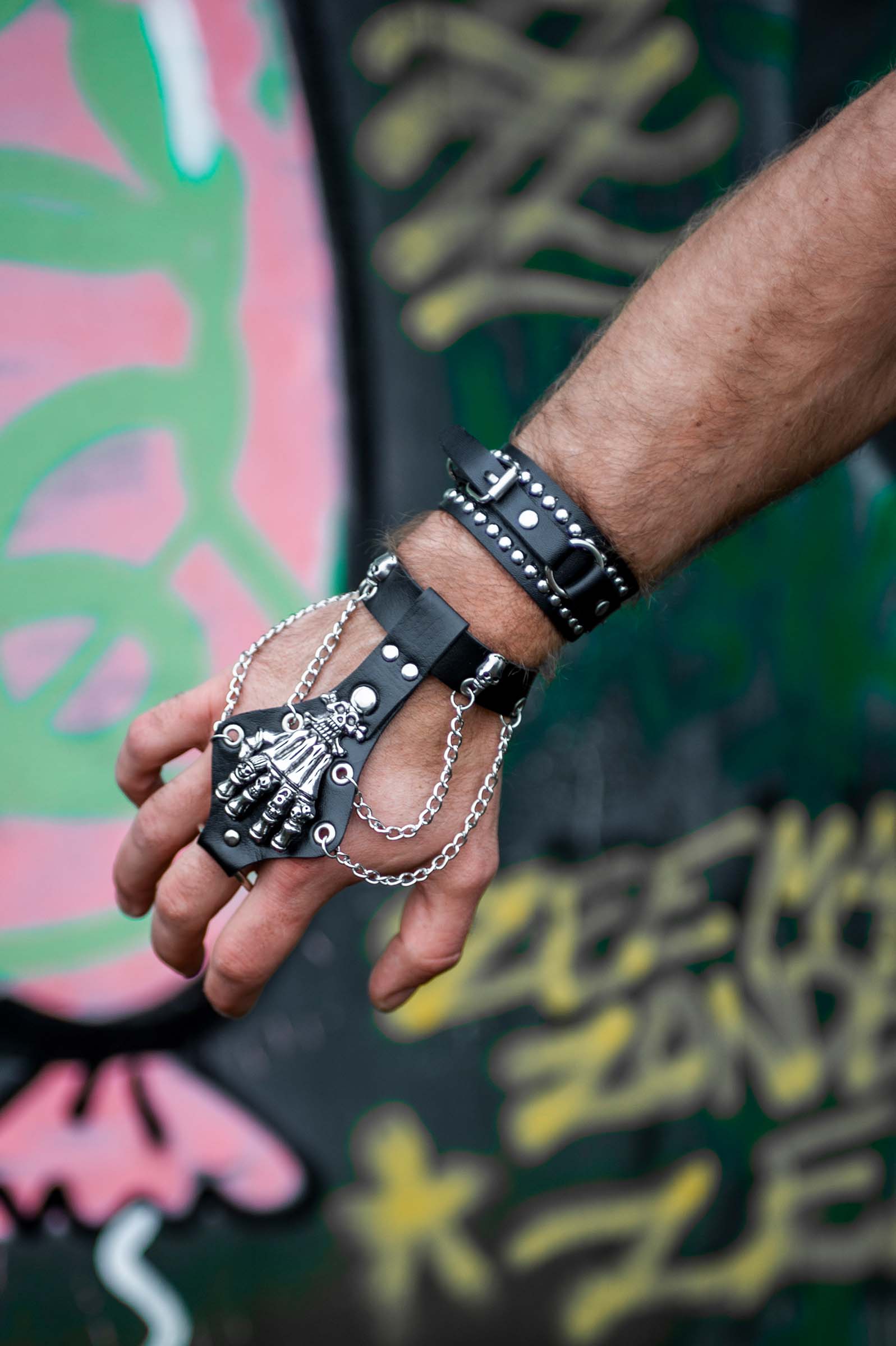 Mannelijk model met close up van arm met rave armband 'bone hand'. een leren armband met een skelethand bovenop en ijzeren kettingen.