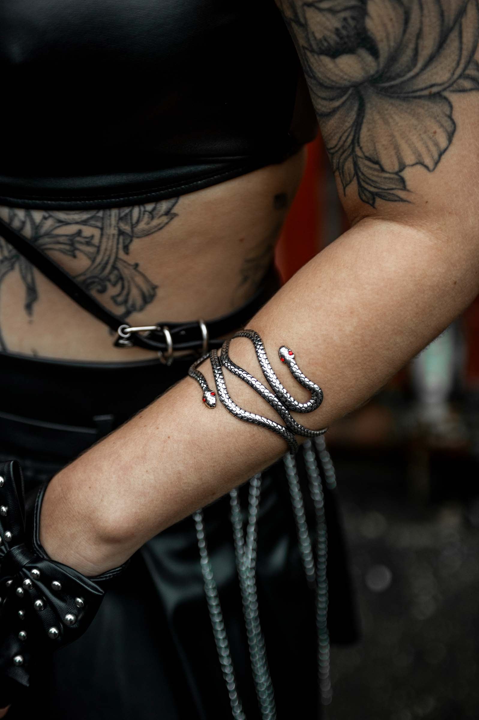 vrouwelijk model met close up arm met rave armband 'iron snake'. Een slang met rode steentjes als ogen