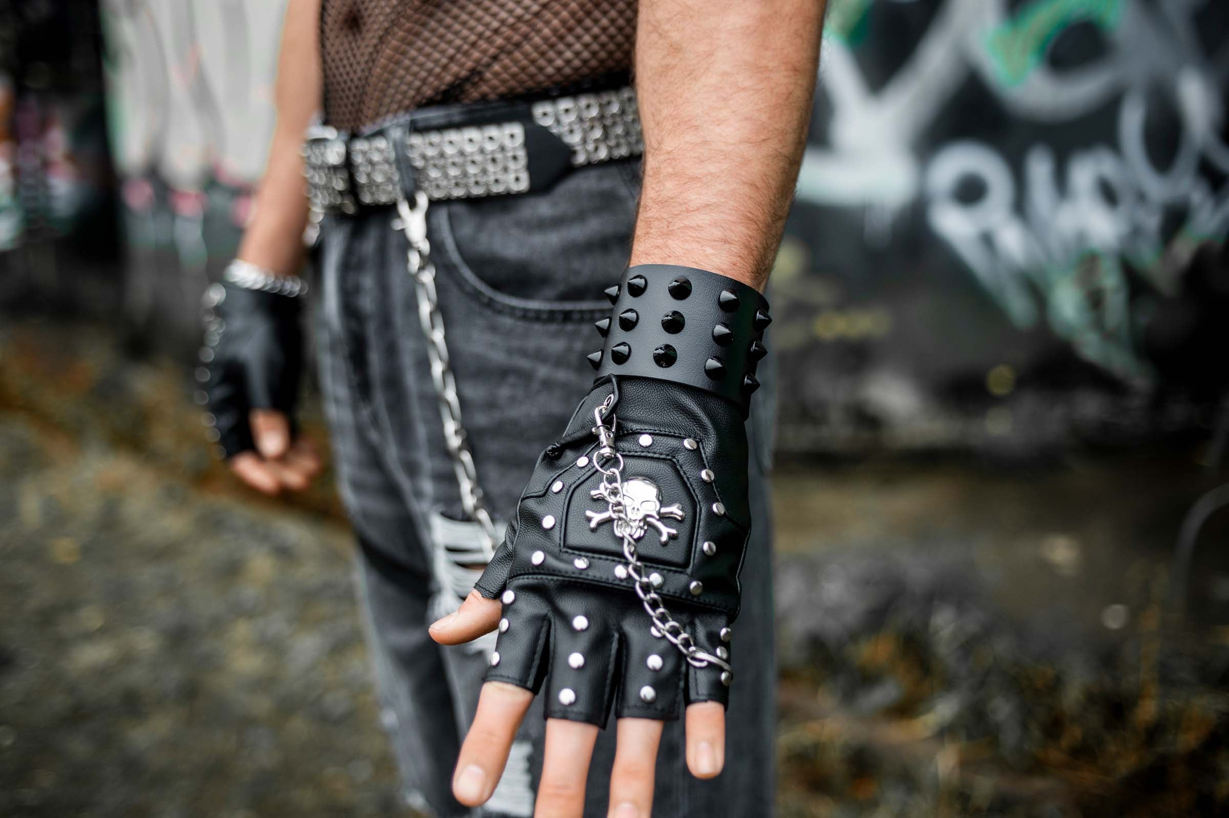 Mannelijk model met close up arm met bovenzijde van rave armband 'black studs'. een leren armband met zwarte studs. 