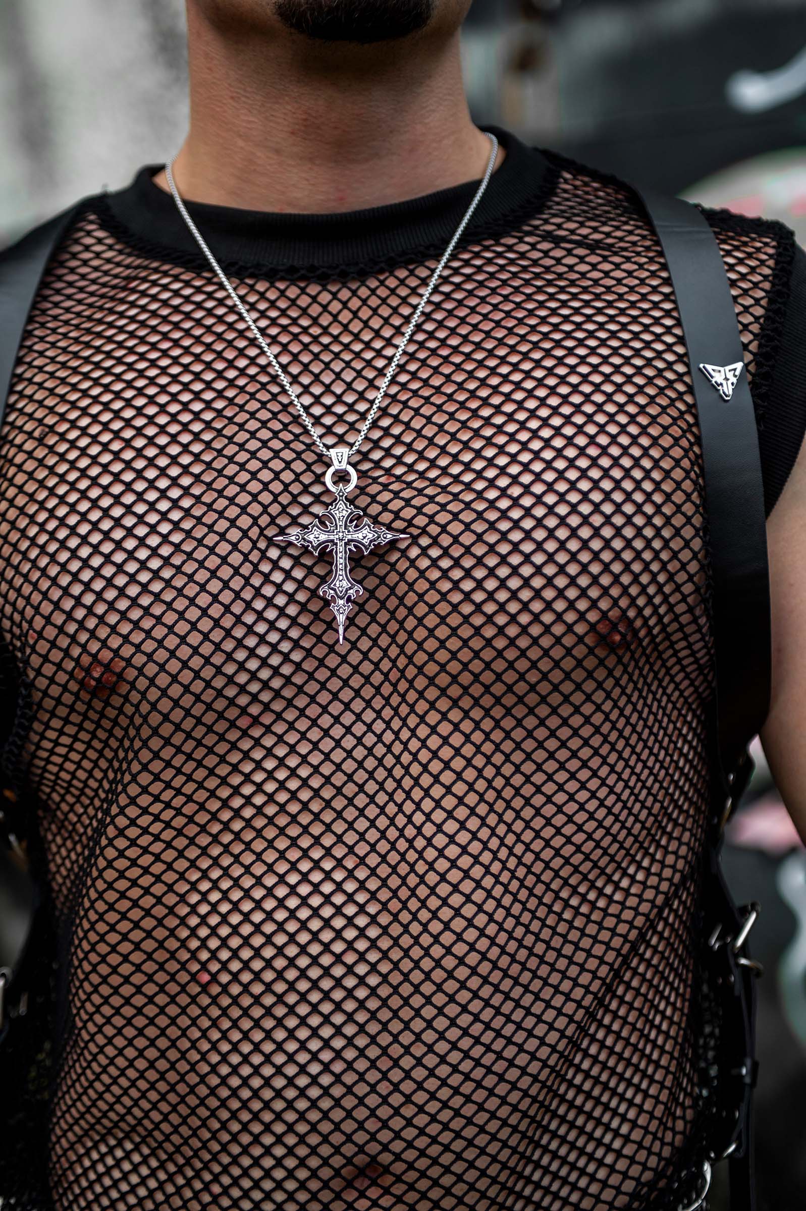 Model met  'Dark Cross' rave ketting van RARE RAVERS, een zilveren ketting met een groot kruis van 8,5 cm, perfect voor een unieke en opvallende rave- of techno-look.