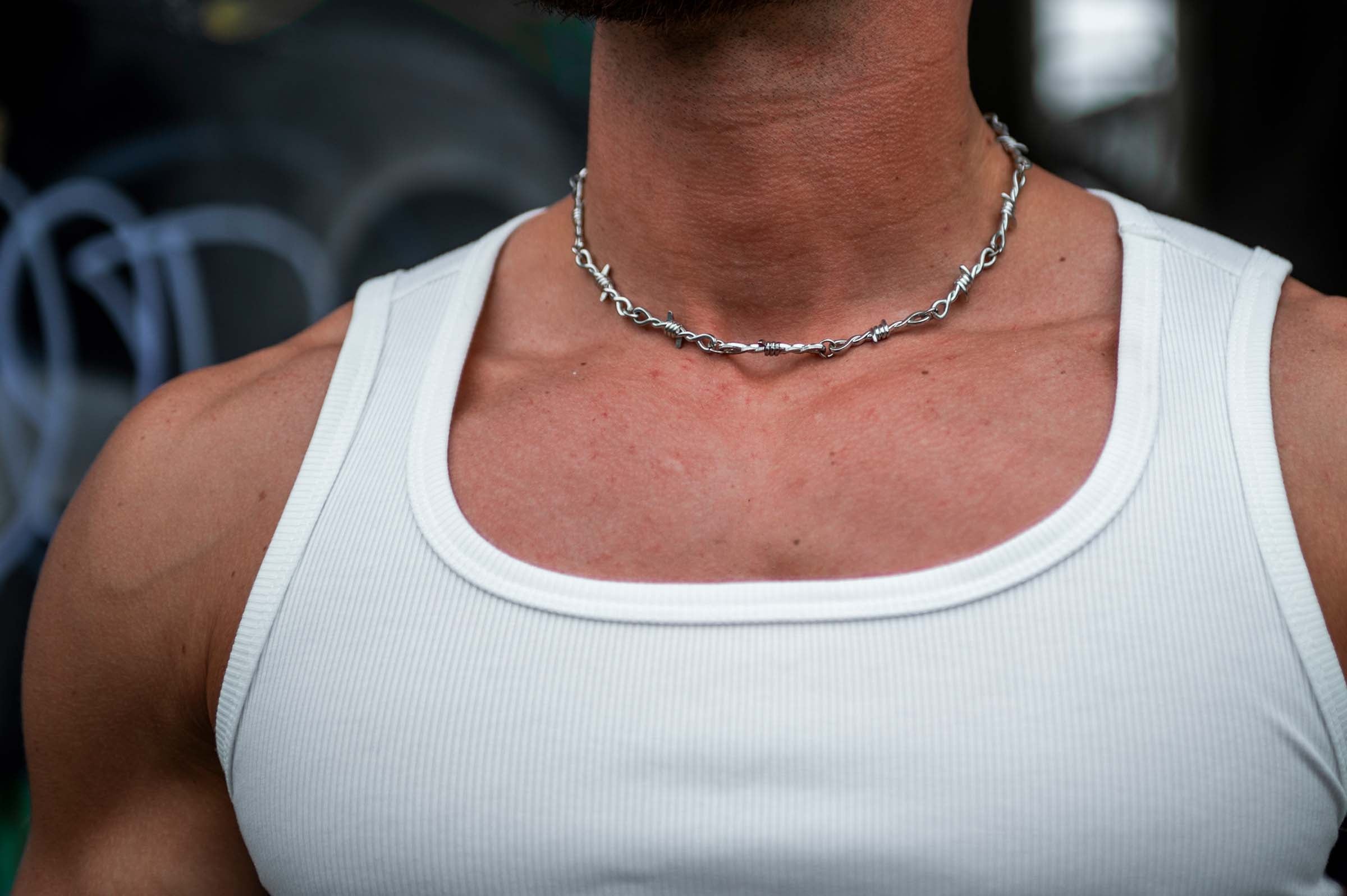 Model draagt de 'Barbed Wire' rave ketting van RARE RAVERS, een zilveren ketting met prikkeldraadontwerp, perfect voor een industriële en stoere look tijdens festivals of techno raves.